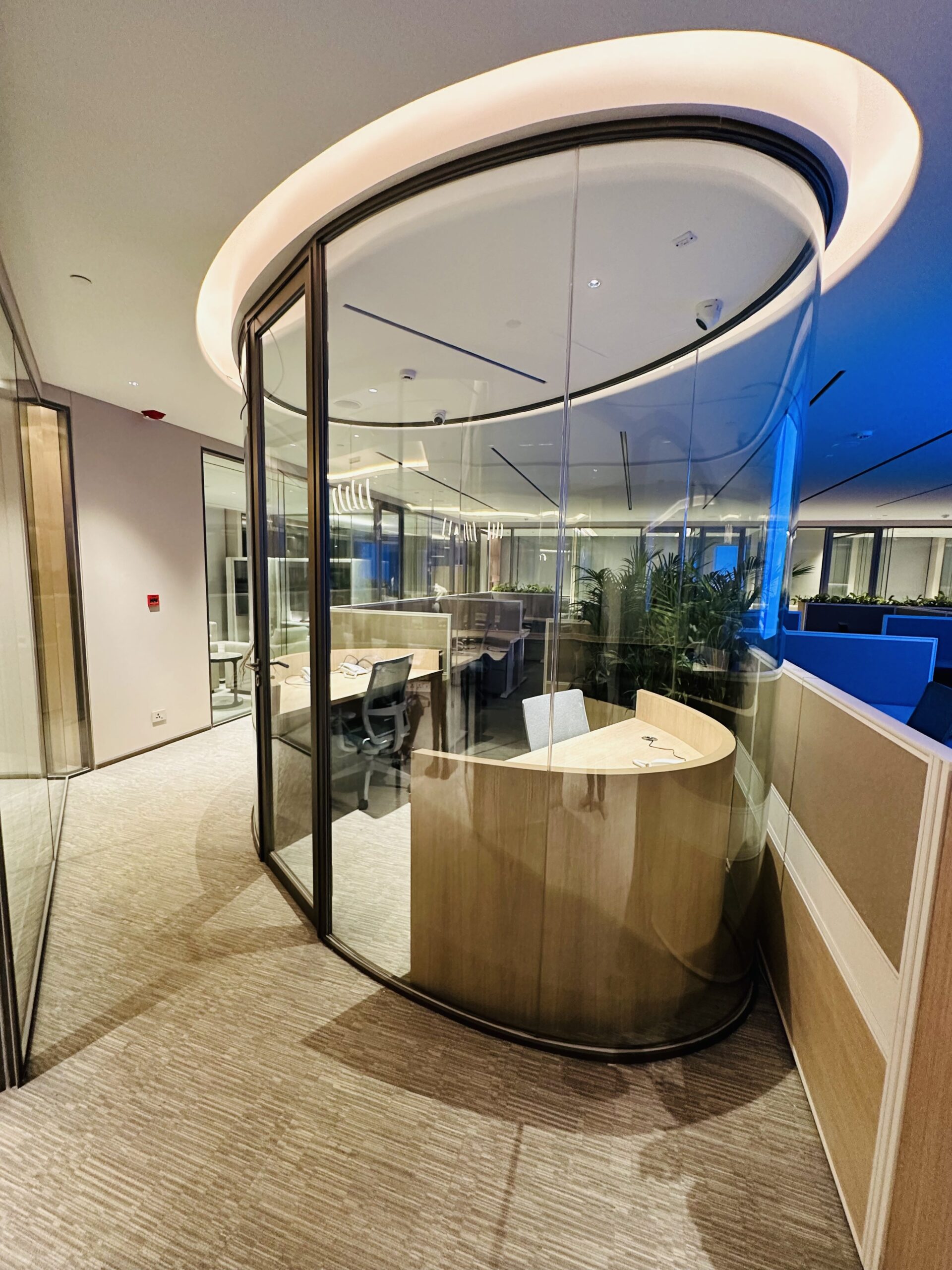 Curved glass partition in a blue-lit office